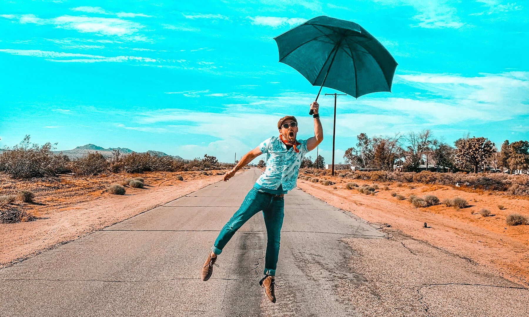Ein Mann hält einen Regenschirm und steht auf einer verlassenen Straße.