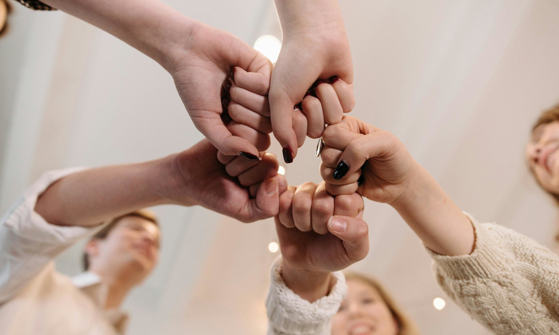 Eine Gruppe von Menschen machen die Fäuste in der Mitte zusammen.
